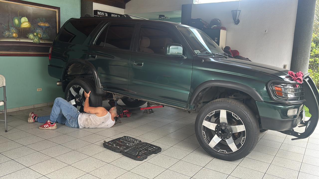 Toyota 4Runner verde levantada con las ruedas fuera mientras se trabaja debajo del vehiculo
